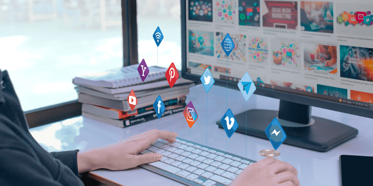 A person typing on a keyboard adorned with various social media icons, emphasizing digital communication.